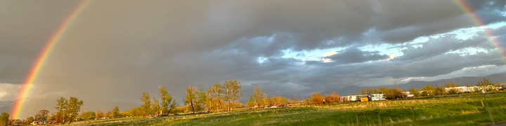 Full rainbow with grey skies and green land